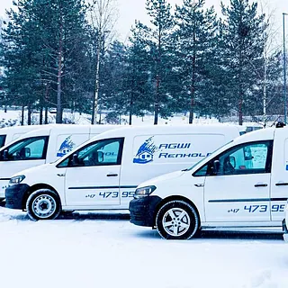 Mann måker snø med skianlegg i bakgrunnen