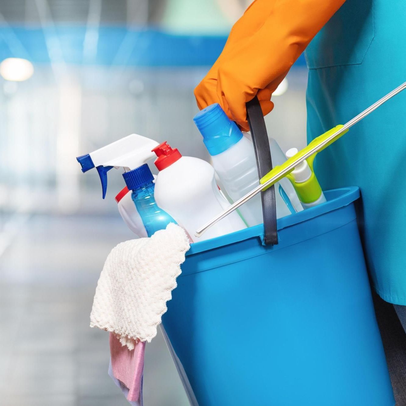 Person holder en bøtte med diverse rengjøringsmidler