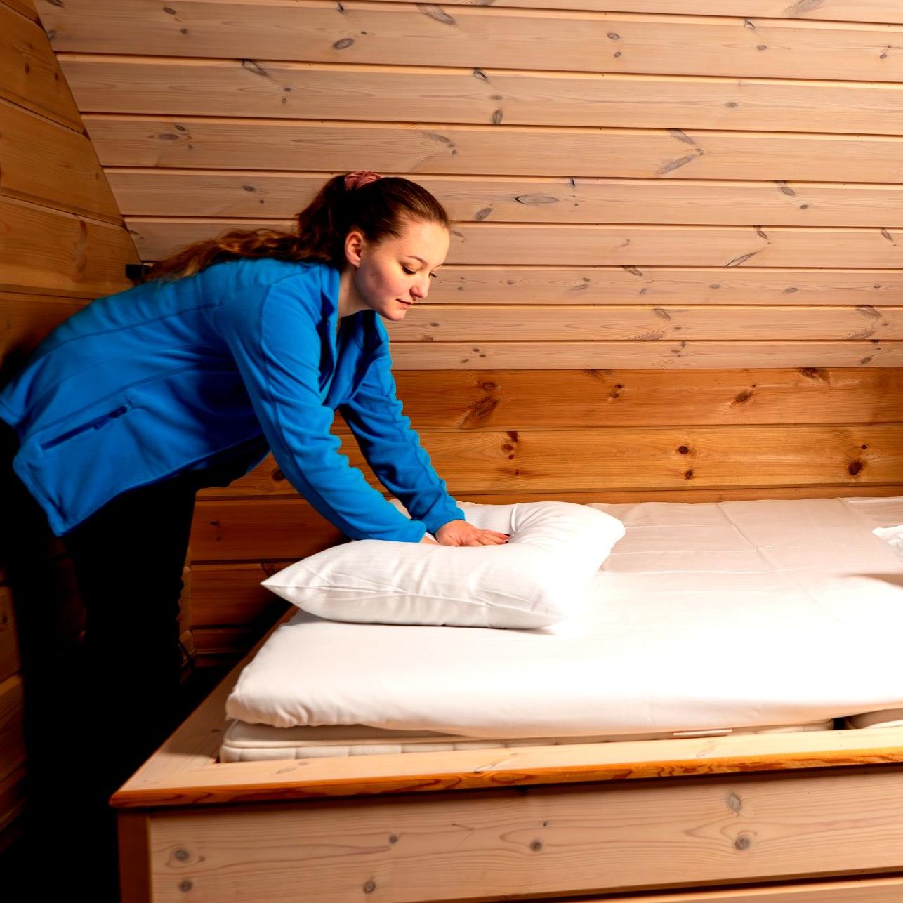 Paulina rer opp seng på hytte